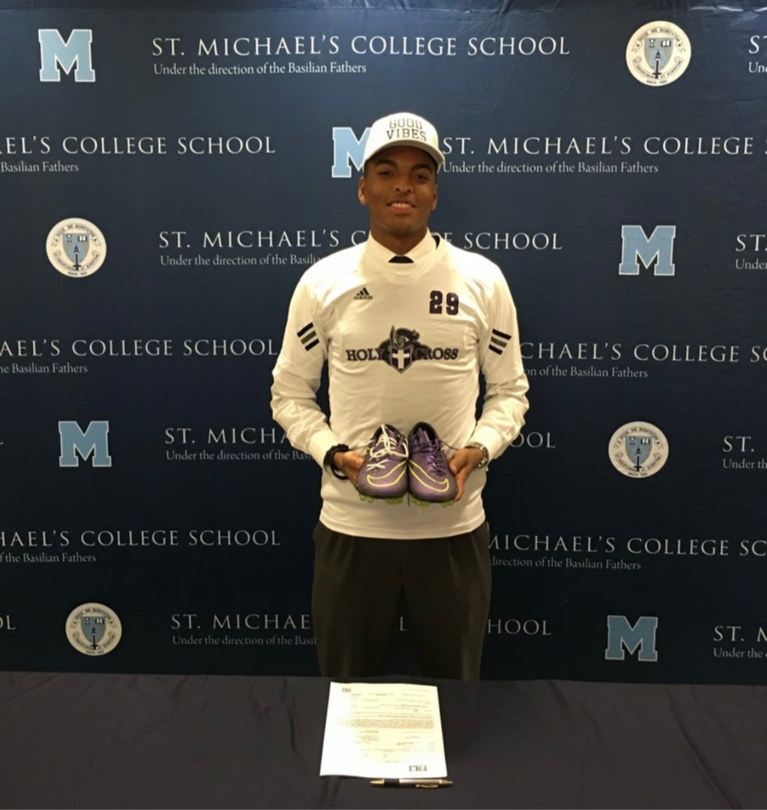 Pathwai's founder on signing day in a Holy Cross jersey, holding a pair of cleats